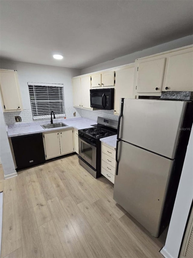 kitchen with sink, decorative backsplash, black appliances, and light hardwood / wood-style floors