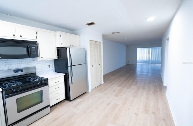 kitchen featuring stainless steel appliances, white cabinetry, tasteful backsplash, and light hardwood / wood-style floors