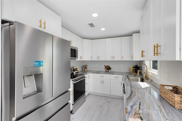 kitchen with white cabinetry, sink, light stone counters, stainless steel appliances, and light hardwood / wood-style flooring