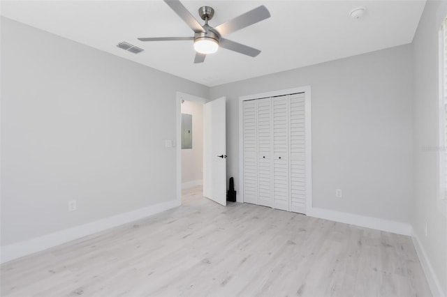 unfurnished bedroom featuring ceiling fan, electric panel, light wood-type flooring, and a closet