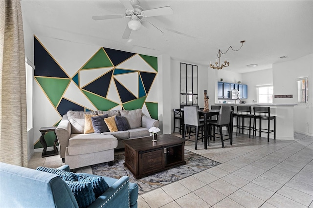 tiled living room featuring ceiling fan with notable chandelier