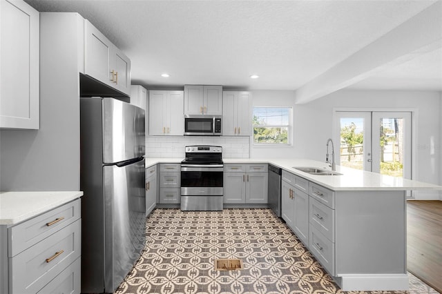 kitchen with stainless steel appliances, kitchen peninsula, sink, and gray cabinetry