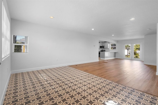 unfurnished living room with wood-type flooring and french doors