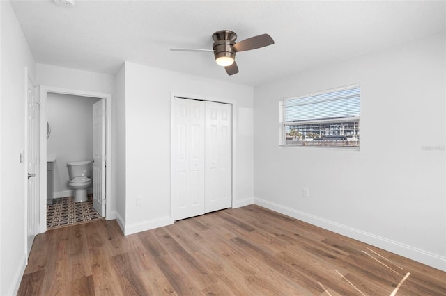 unfurnished bedroom with ensuite bathroom, hardwood / wood-style floors, ceiling fan, and a closet