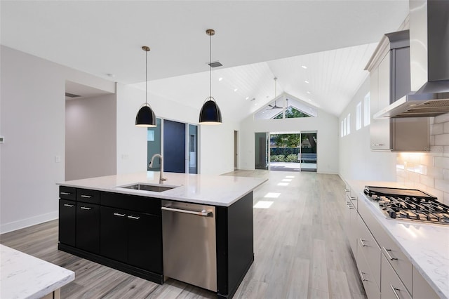 kitchen with white cabinetry, hanging light fixtures, an island with sink, decorative backsplash, and wall chimney range hood