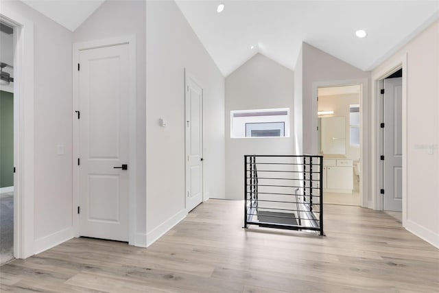 hall with lofted ceiling and light hardwood / wood-style floors