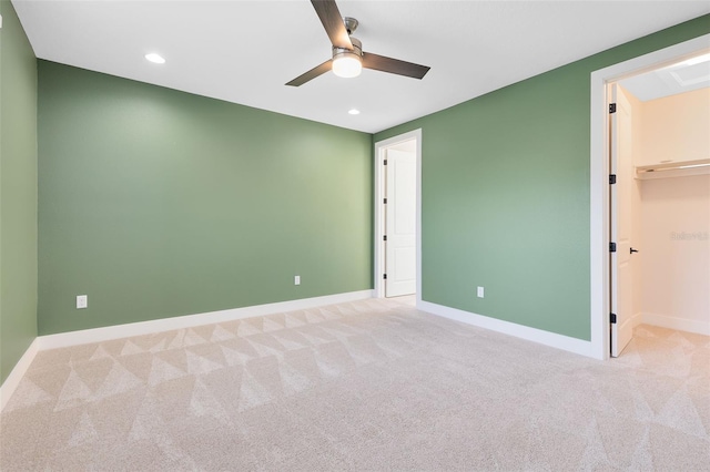 unfurnished bedroom featuring a walk in closet, light colored carpet, and ceiling fan