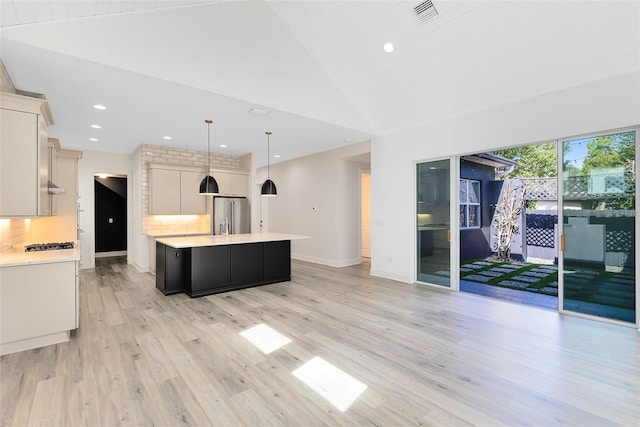 kitchen with tasteful backsplash, decorative light fixtures, a center island, stainless steel appliances, and light hardwood / wood-style floors