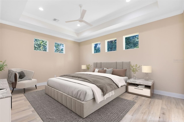 bedroom featuring ceiling fan, a raised ceiling, and light wood-type flooring