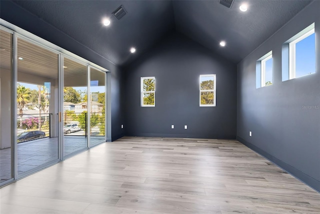 empty room featuring high vaulted ceiling, a healthy amount of sunlight, and light wood-type flooring