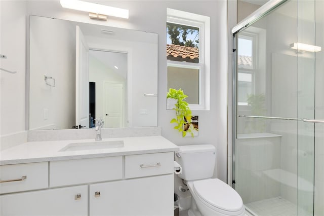 bathroom featuring vanity, toilet, and a shower with shower door