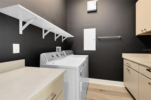 clothes washing area featuring light hardwood / wood-style floors, cabinets, and washing machine and clothes dryer