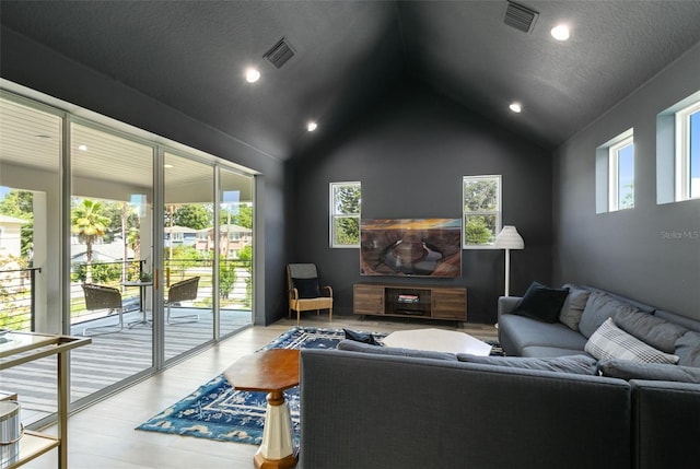 living area with vaulted ceiling, visible vents, a textured ceiling, and wood finished floors