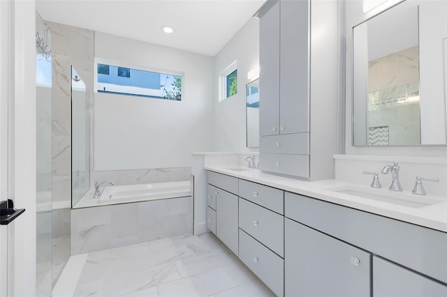full bathroom with double vanity, a bath, marble finish floor, and a sink