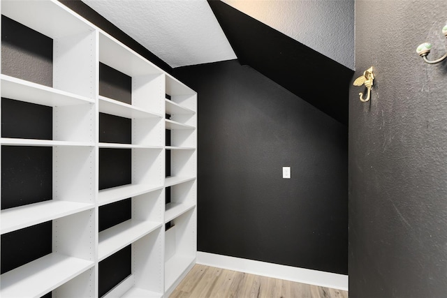 spacious closet with lofted ceiling and wood finished floors