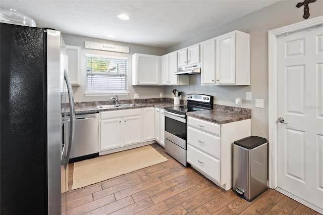 kitchen with white cabinetry, stainless steel appliances, sink, and a textured ceiling