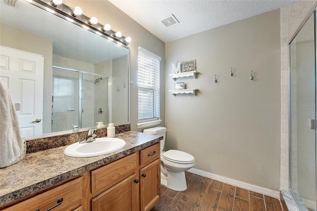 bathroom with vanity, a shower with door, and a textured ceiling