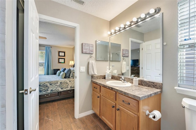 bathroom with vanity, toilet, hardwood / wood-style floors, and a textured ceiling