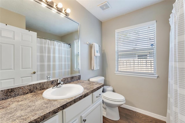 bathroom featuring vanity, a healthy amount of sunlight, hardwood / wood-style floors, and toilet