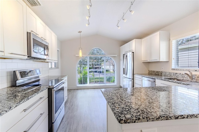 kitchen featuring vaulted ceiling, appliances with stainless steel finishes, pendant lighting, white cabinets, and light wood-type flooring