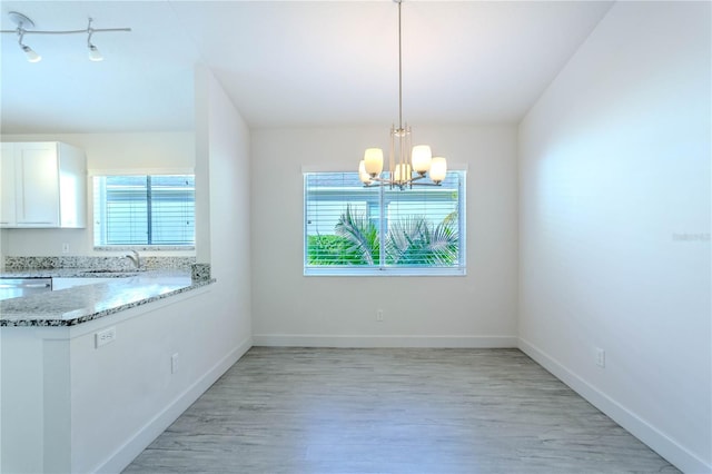 unfurnished dining area with sink, light hardwood / wood-style flooring, and a chandelier