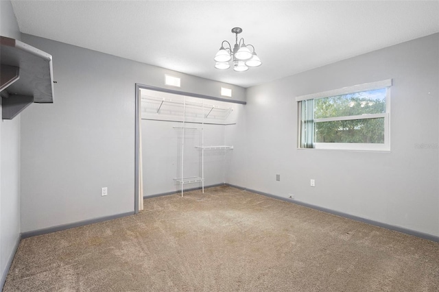 unfurnished bedroom featuring carpet floors, a closet, and a chandelier