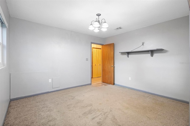 spare room with a notable chandelier and light colored carpet