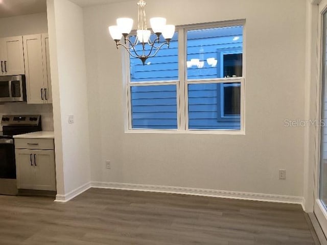 unfurnished dining area featuring dark wood-type flooring and a chandelier