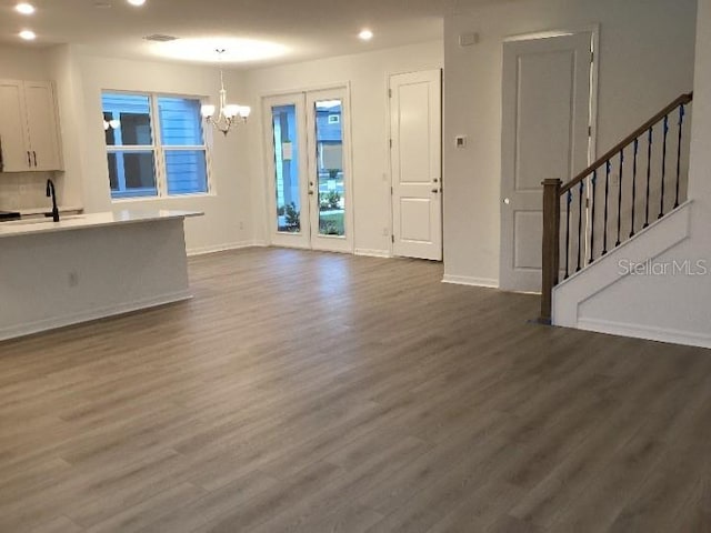 unfurnished living room with dark hardwood / wood-style floors, sink, and a chandelier