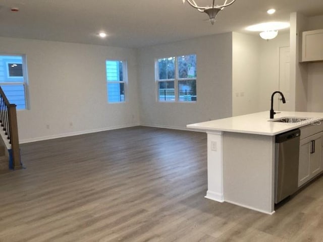 kitchen with a kitchen island with sink, wood-type flooring, stainless steel dishwasher, and white cabinets