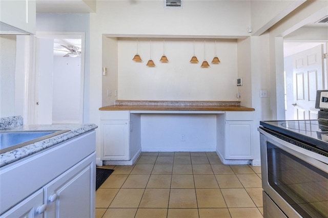 kitchen with stainless steel range with electric cooktop, decorative light fixtures, built in desk, ceiling fan, and white cabinets