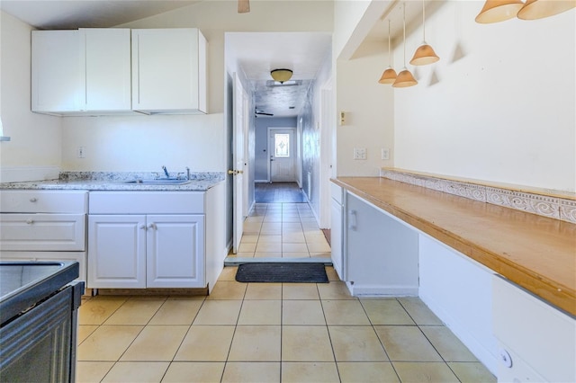 kitchen with sink, decorative light fixtures, light tile patterned floors, and white cabinets