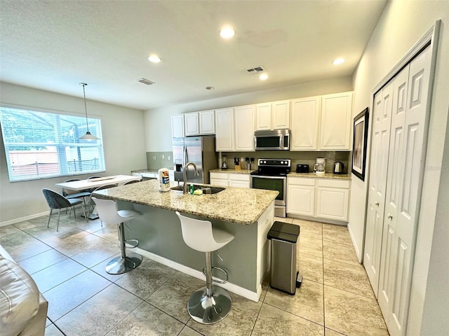 kitchen with appliances with stainless steel finishes, decorative light fixtures, sink, a kitchen breakfast bar, and a center island with sink