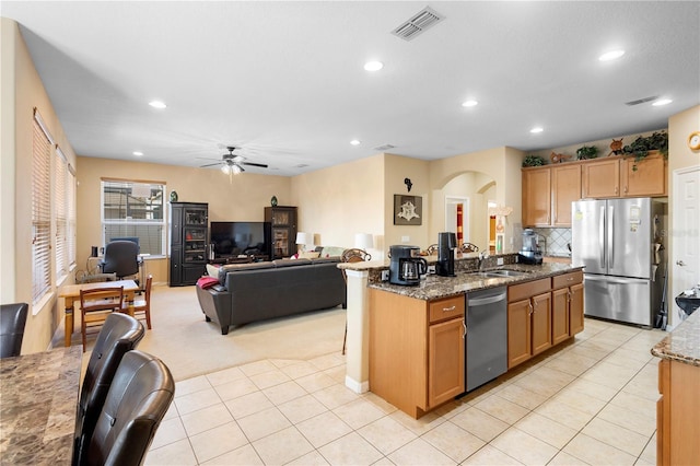 kitchen featuring sink, a center island with sink, stone counters, and appliances with stainless steel finishes