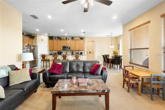 carpeted living room with ceiling fan