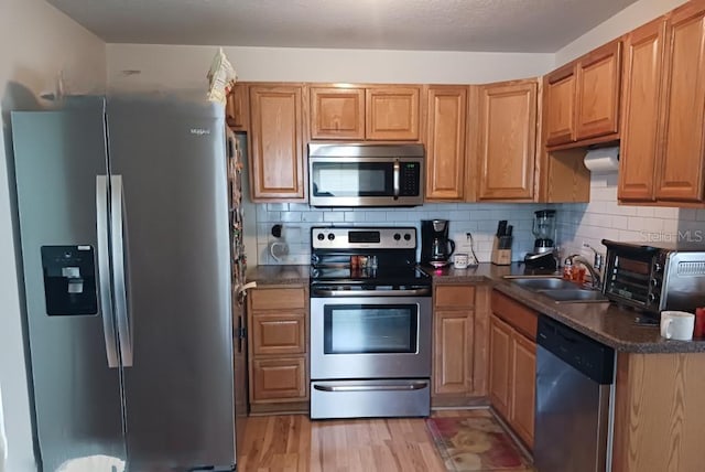 kitchen featuring tasteful backsplash, appliances with stainless steel finishes, sink, and light wood-type flooring