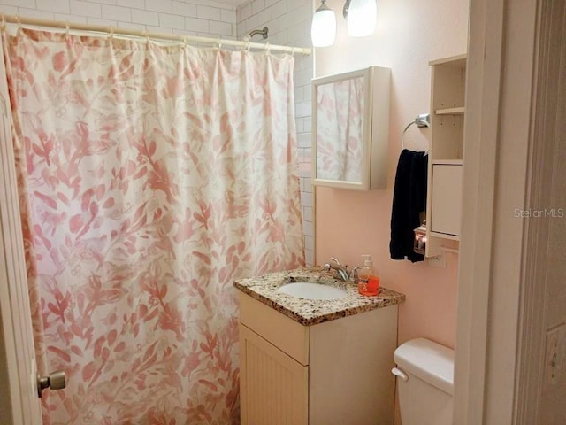 bathroom with walk in shower, vanity, and toilet