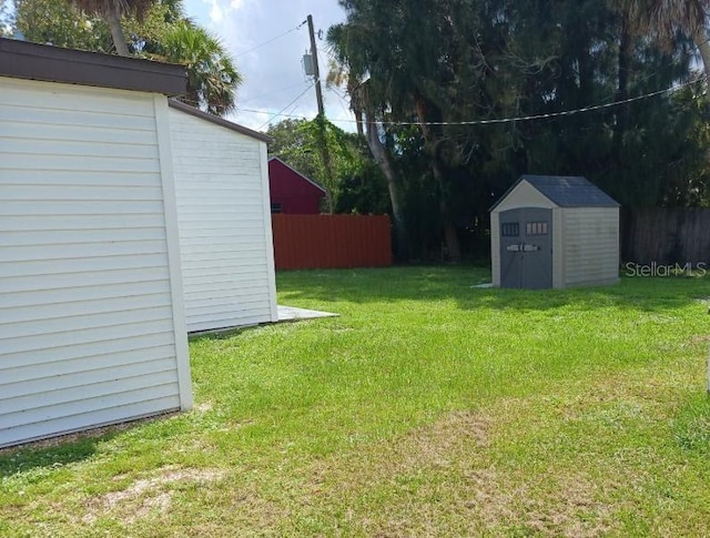 view of yard with a storage shed, an outdoor structure, and fence