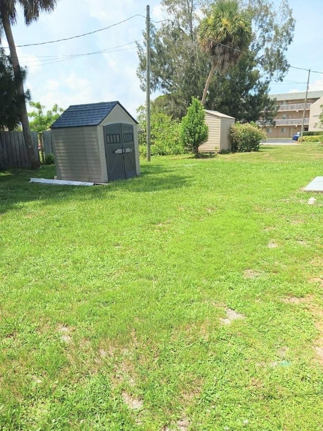 view of yard with an outbuilding, a storage shed, and fence