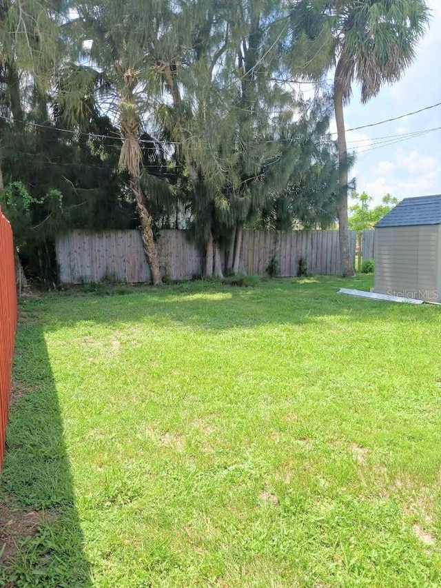 view of yard with an outbuilding, a fenced backyard, and a shed