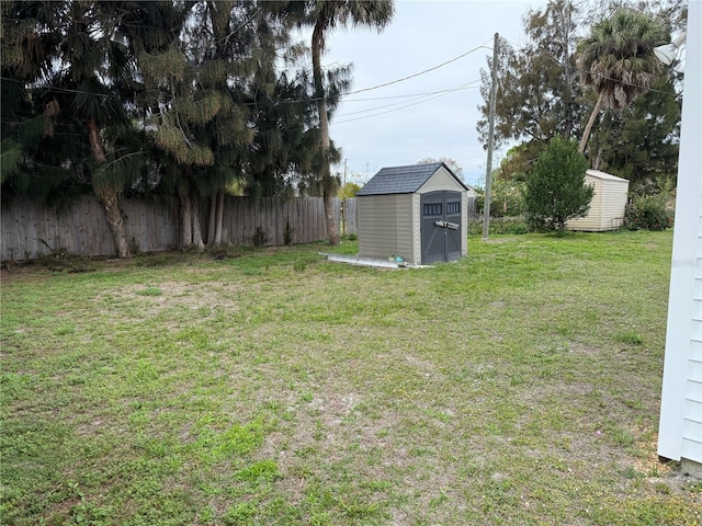 view of yard with a storage shed, fence, and an outbuilding