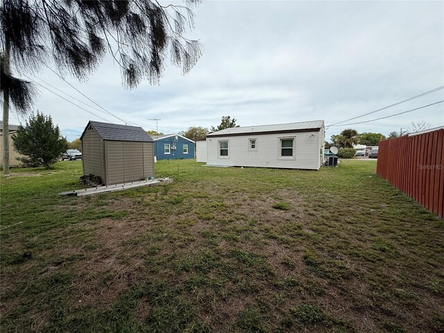 view of yard featuring an outbuilding, fence, and a shed