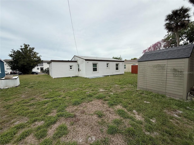 back of house featuring a lawn, a storage unit, and an outdoor structure