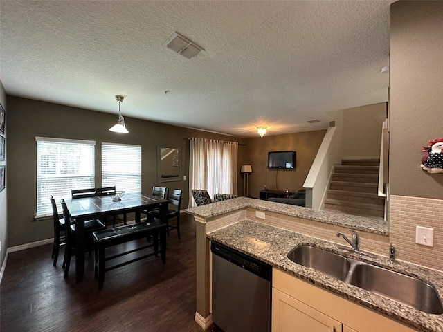 kitchen featuring dishwasher, sink, hanging light fixtures, light stone countertops, and a textured ceiling