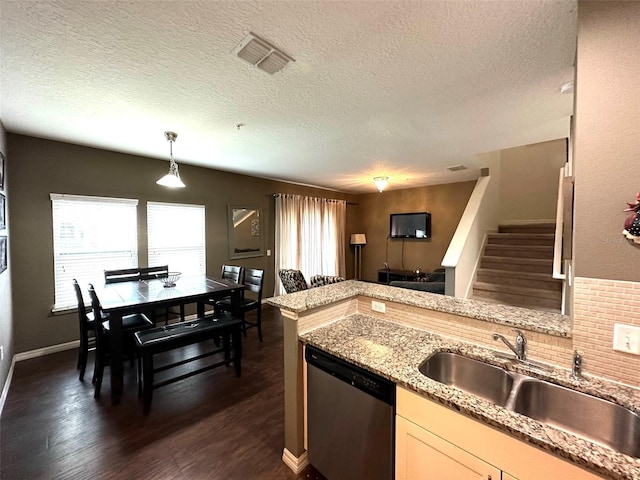 kitchen featuring sink, hanging light fixtures, stainless steel dishwasher, light stone countertops, and a textured ceiling