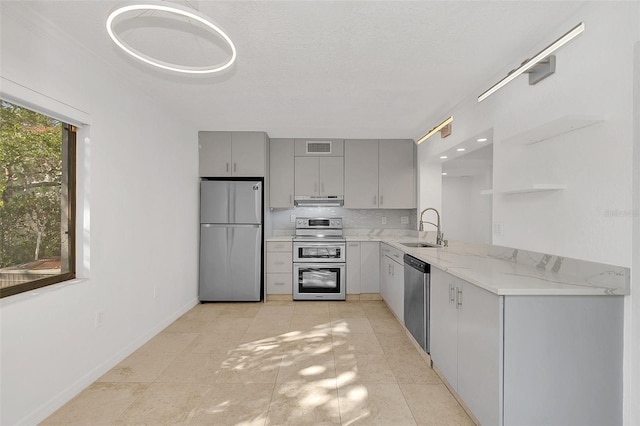 kitchen with gray cabinets, open shelves, under cabinet range hood, appliances with stainless steel finishes, and a sink