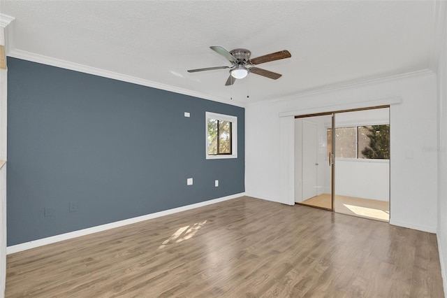 unfurnished bedroom featuring a closet, baseboards, crown molding, and wood finished floors