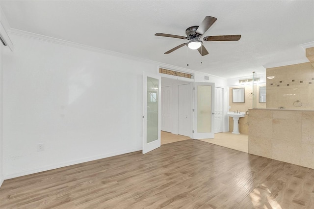 unfurnished living room featuring a sink, ornamental molding, ceiling fan, and light wood finished floors
