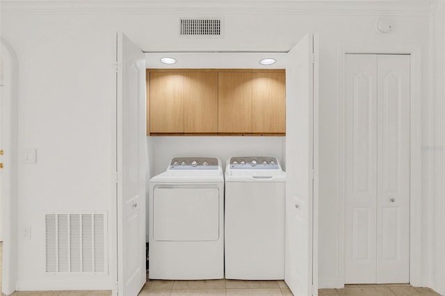 laundry area featuring visible vents, light tile patterned flooring, separate washer and dryer, and cabinet space