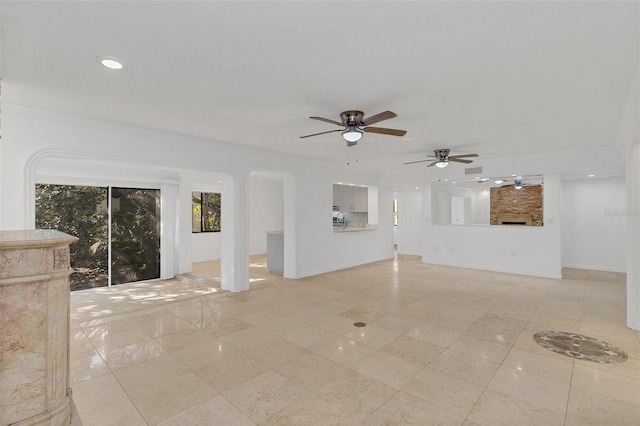 unfurnished living room with baseboards, recessed lighting, light tile patterned flooring, ceiling fan, and arched walkways